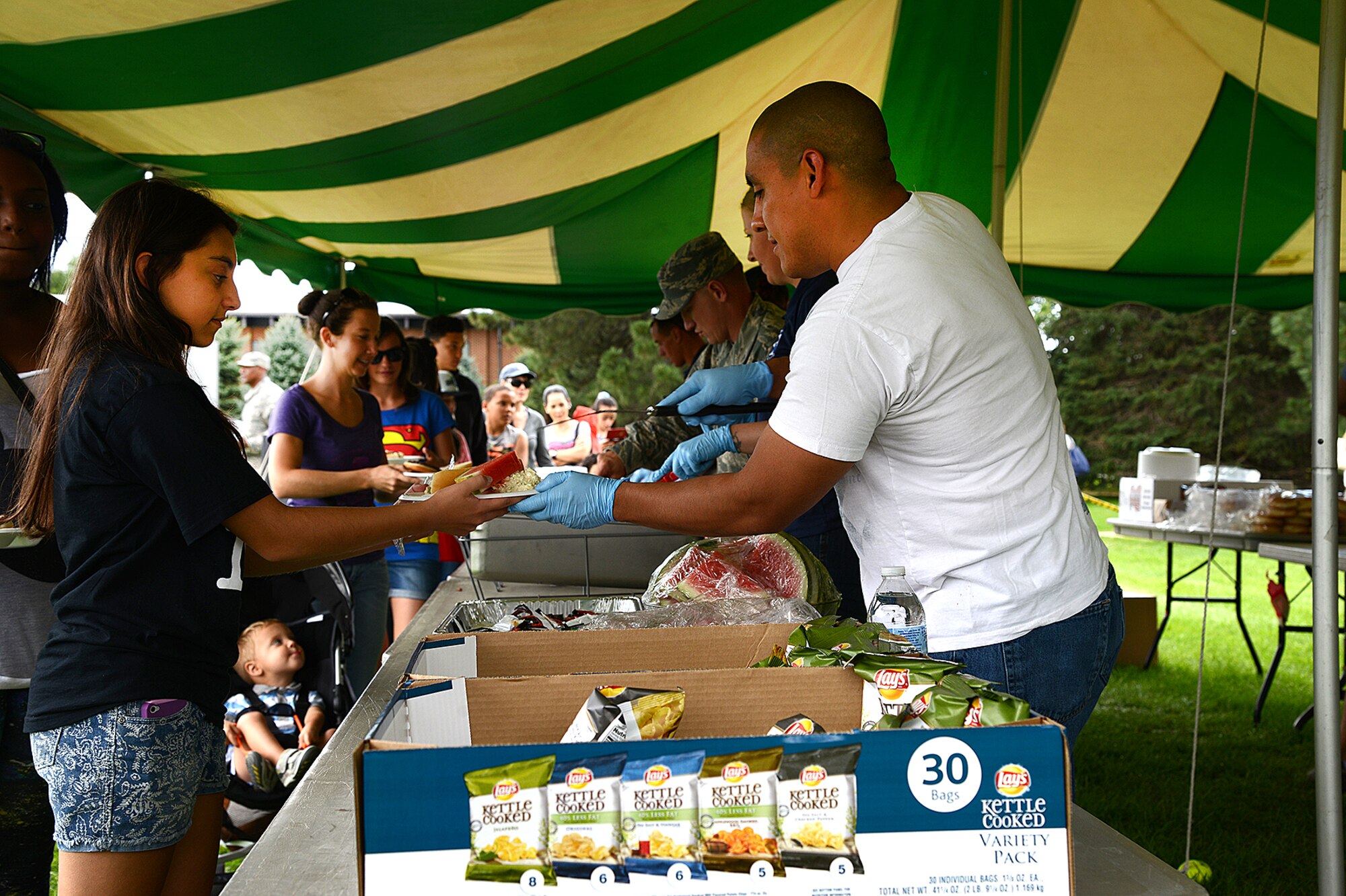 PETERSON AIR FORCE BASE, Colo. — Master Sgt. Jesus Revilla, 21 Civil Engineer Squadron acting First Sergeant, hands plates of food to each person to pass through the food line at the annual Family Festival and Concert held at Patriot Park Aug. 8. The event was open to all base personnel and their families and included food, beverages, inflatables, old fashioned games and live music. (U.S. Air Force photo/Airman 1st Class Rose Gudex)