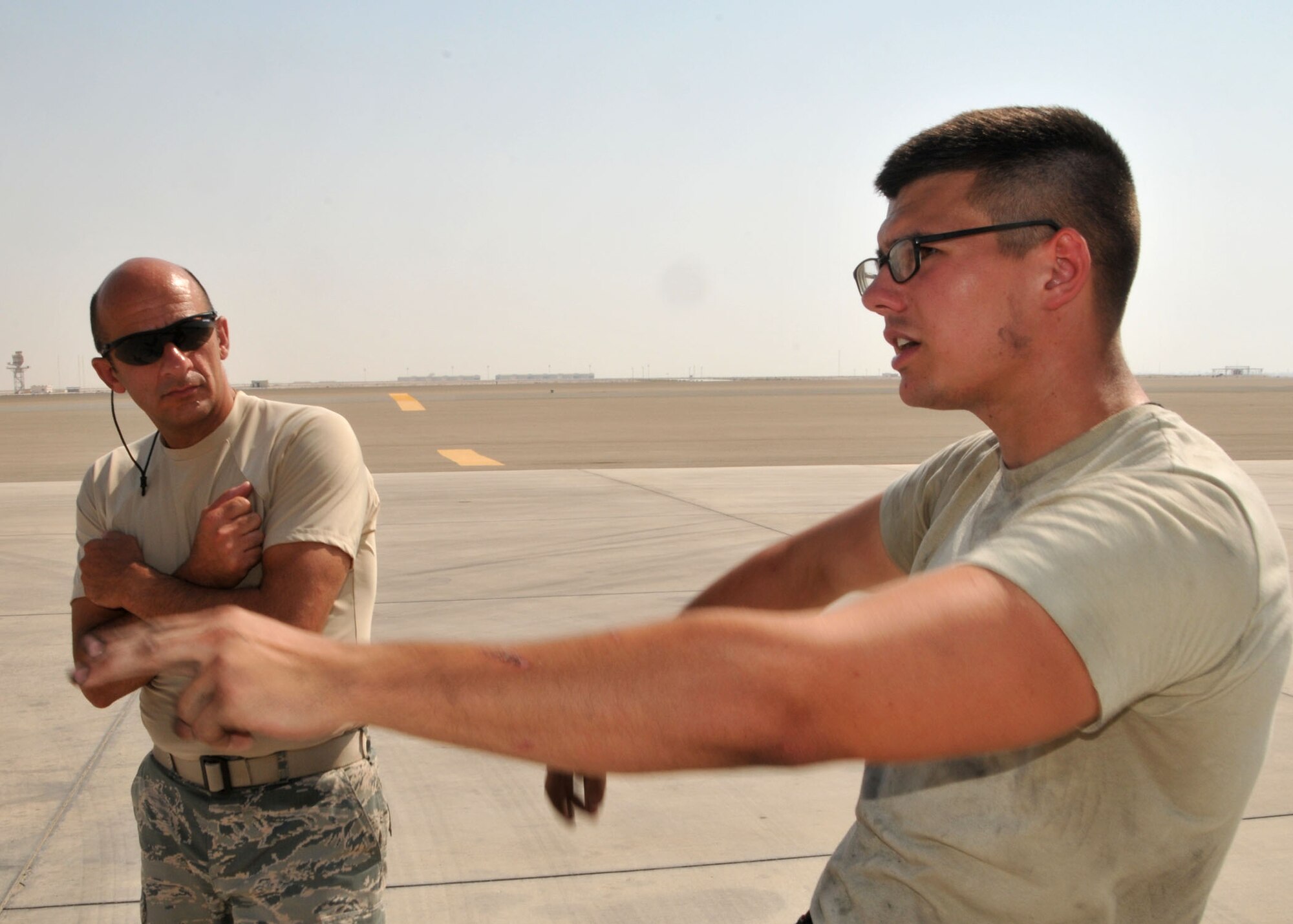 Air Force Airman 1st Class Spencer Watson shows Command Chief Master Sgt. Samer Alkhoury aircraft marshalling techniques at the 380th Air Expeditionary Wing flightline June 21, 2014. (U.S. Air Force photo by Senior Master Sgt. Eric Peterson/Released)
