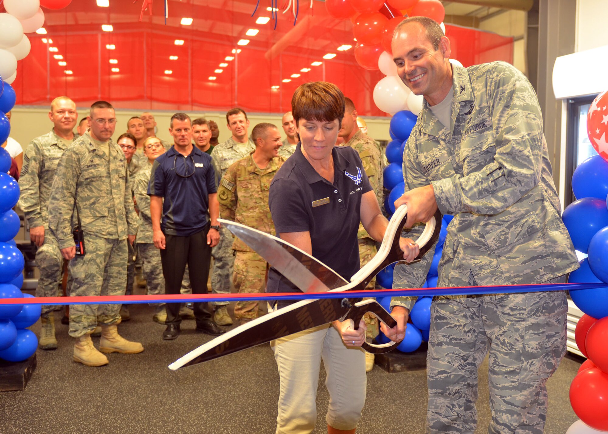 380th Air Expeditionary Wing Vice Commander Col. C. Jeffrey Cooper cuts the ceremonial ribbon with Fitness and Sports Director Lesley Sparks during the grand opening of the new base fitness center in Southwest Asia Aug. 9, 2014. (U.S. Air Force photo by Maj. Jefferson S. Heiland)

