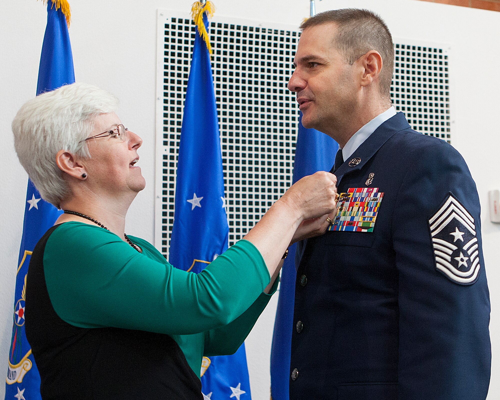 Pat Nordel affixes the Air Force retirement pin on the uniform of her husband, Chief Master Sgt. David Nordel, during his retirement ceremony August 8, 2014, in Fall Hall on F.E. Warren Air Force Base, Wyo. Nordel finished out his 30-year career as the 20th Air Force command chief. (U.S. Air Force photo by R.J. Oriez)