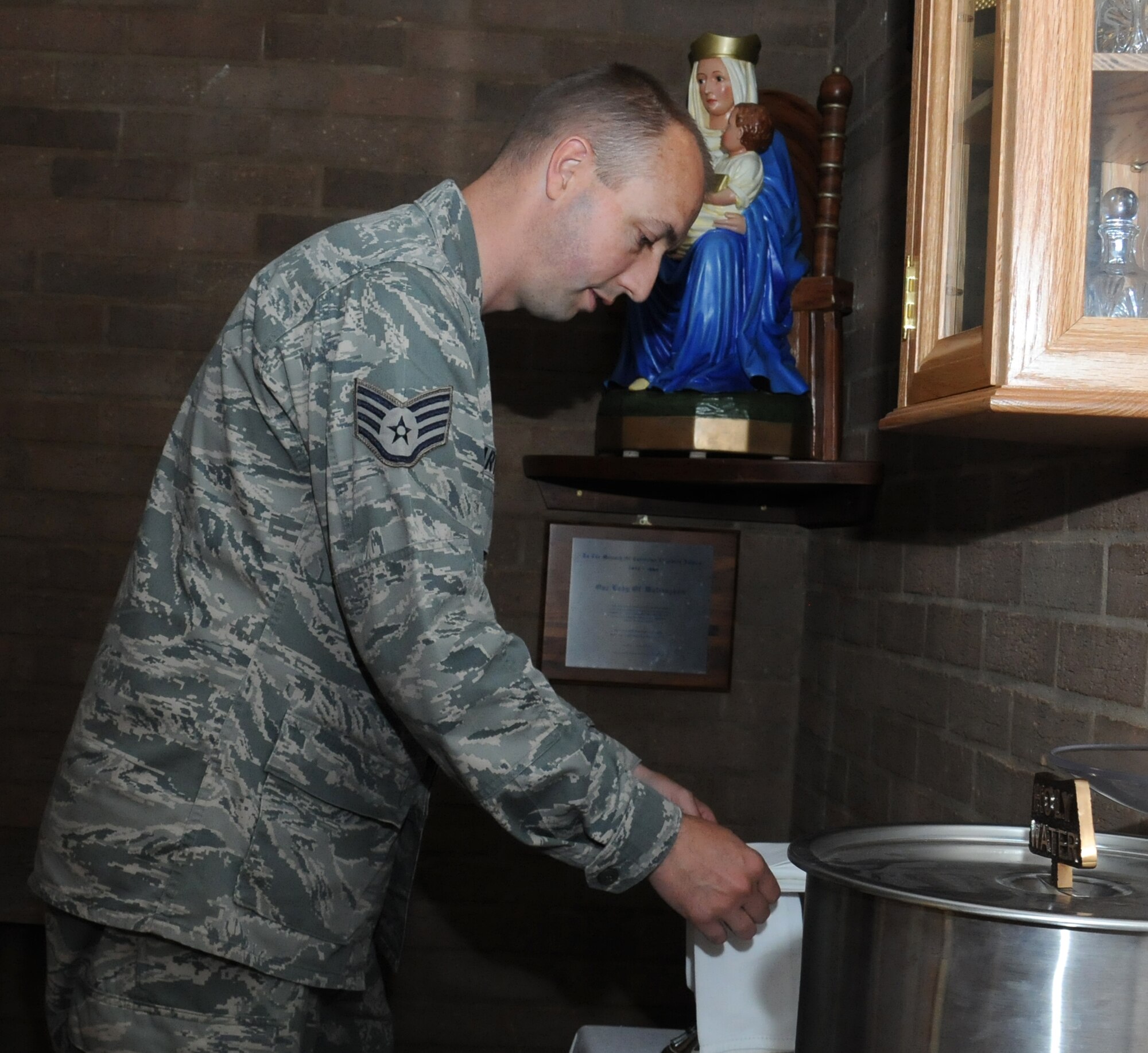 U.S. Air Force Staff Sgt. Joshua Hartvigsen, 100th Air Refueling Wing NCO in charge of chapel readiness and training from Bountiful, Utah, arranges Mass for the congregation Aug. 6, 2014, in the chapel on RAF Mildenhall, England. In his role as a chaplain assistant, Hartvigsen takes care of logistics in the chapel, including facilities, finances, and readiness and training. (U.S. Air Force photo/Gina Randall/Released)