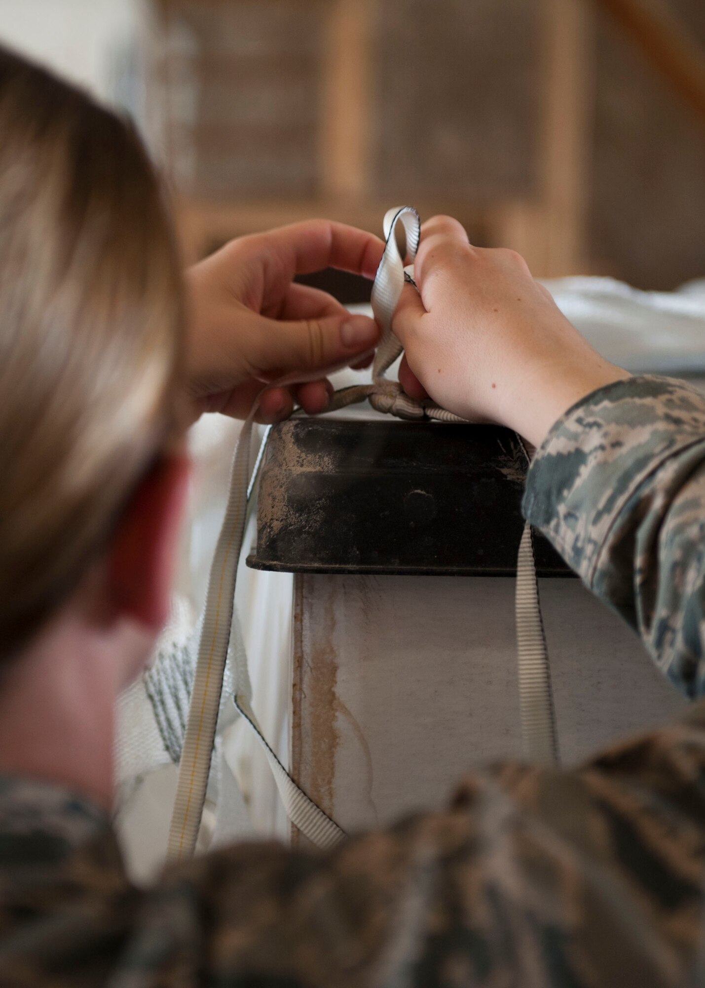 U.S. Air Force Capt. Kristin Swenson, chaplain, ties a knot for a tie on a pallet at a location in Southwest Asia Aug., 11, 2014. Volunteers from across the base came out to help build pallets of humanitarian aid. The pallets consist of food and water for humanitarian aid drops to assist displaced citizens in the vicinity of Sinjar, Iraq. (U.S. Air Force photo by Senior Airman Colin Cates)