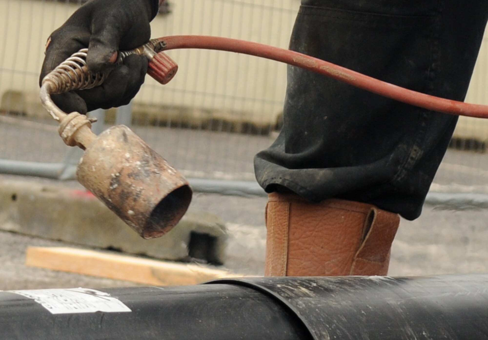 A contractor uses a heat gun on a pipe Aug. 8, 2014, on RAF Mildenhall, England. The gun is used to seal a weld point on the pipe to prevent contamination. (U.S. Air Force photo/Airman 1st Class Jonathan Light/Released)
