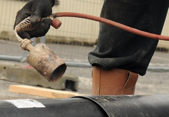 A contractor uses a heat gun on a pipe Aug. 8, 2014, on RAF Mildenhall, England. The gun is used to seal a weld point on the pipe to prevent contamination. (U.S. Air Force photo/Airman 1st Class Jonathan Light/Released)