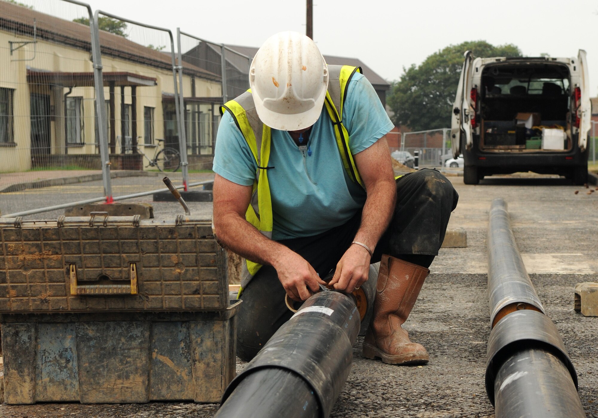Allan Bates, a contractor from North Hampshire, England, stabilizes wires on a pipe Aug. 8, 2014, on RAF Mildenhall. The wires help detect if the new heating system, being installed near the 100th Air Refueling Wing command post, has been contaminated by moisture. (U.S. Air Force photo/Airman 1st Class Jonathan Light/Released)