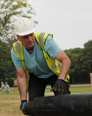 Allan Bates, a contractor from North Hampshire, England, picks up a pipe Aug. 8, 2014, on RAF Mildenhall, England. The pipe is a part of a new heating system that is replacing an out dated one near the base command post. (U.S. Air Force photo/Airman 1st Class Jonathan Light/Released)