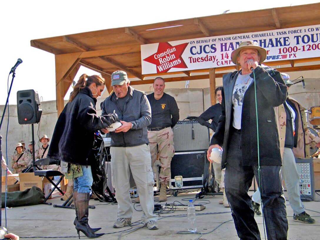 Celebrities Lee Ann Tweeden and Charles Clark autograph footballs that comedian Robin Williams will toss to U.S. troops on Camp Al Tahreer in Baghdad, Dec. 14, 2004.