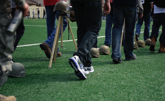 Ninety-nine helmets representing sexual assault cases dating back 10 years line the field as Airmen walk past them during the base-wide Sexual Assault Prevention and Response down day at Kunsan Air Base, Republic of Korea, May 22, 2014. In between each of the 99 were sets of three representing the statistically unreported cases believed to have occurred on base.(U.S. Air Force photo by Senior Airman Armando A. Schwier-Morales)