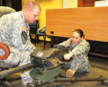 New York Army National Guard Staff Sgt. Douglas Sandburg, an instructor with the 106th Regional Training Institute, instructs Sgt. Patricia Schuett, 222nd Chemical Company, of Woodhaven, N.Y., how to operate and clear a MK 19 Grenade Machine Gun, Aug 4, 2014.   The training is part of a four-week military police reclassification course taught at Camp Smith Training Site, Peekskill, N.Y.  