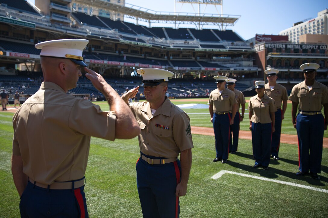 Cpl. Michael Robertson, center, electrician with Marine Wing Support Squadron (MWSS) 373, salutes Chief Warrant Officer 2 Aaron Alcorn, MWSS-373 officer in charge, to start off his re-enlistment ceremony at Petco Park, San Diego, Aug. 13. The ceremony took place before a scheduled baseball game with the San Diego Padres vs. Colorado Rockies. 