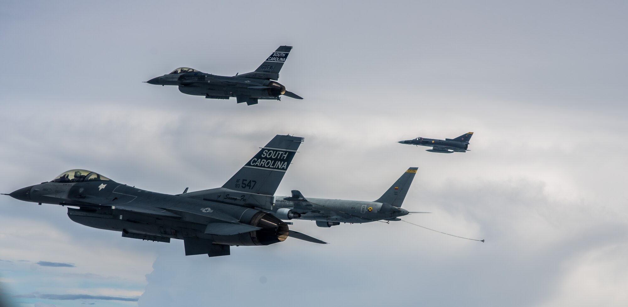 Two South Carolina Air National Guard F-16s fly alongside a Colombian air force Kfir and KC-767 tanker aircraft during a training flight Aug. 12 over Colombia. Nearly 100 Airmen and six F-16s from the 169th Fighter Wing at McEntire Air National Guard Base are participating in the combined air operation engagement, which is the first major joint-air engagement opportunity under the auspices of the South Carolina's State Partnership Program with Colombia. The exercise allows the U.S. and Colombian airmen to share tactics, techniques, and procedures on many subjects including defensive air operations, operations coordination and scheduling, and best maintenance practices; all of which can be applied to maritime, littoral waters, over-land areas of operations, and defense of national territory. (U.S. Air Force photo by Maj. Matt Booth/Released)