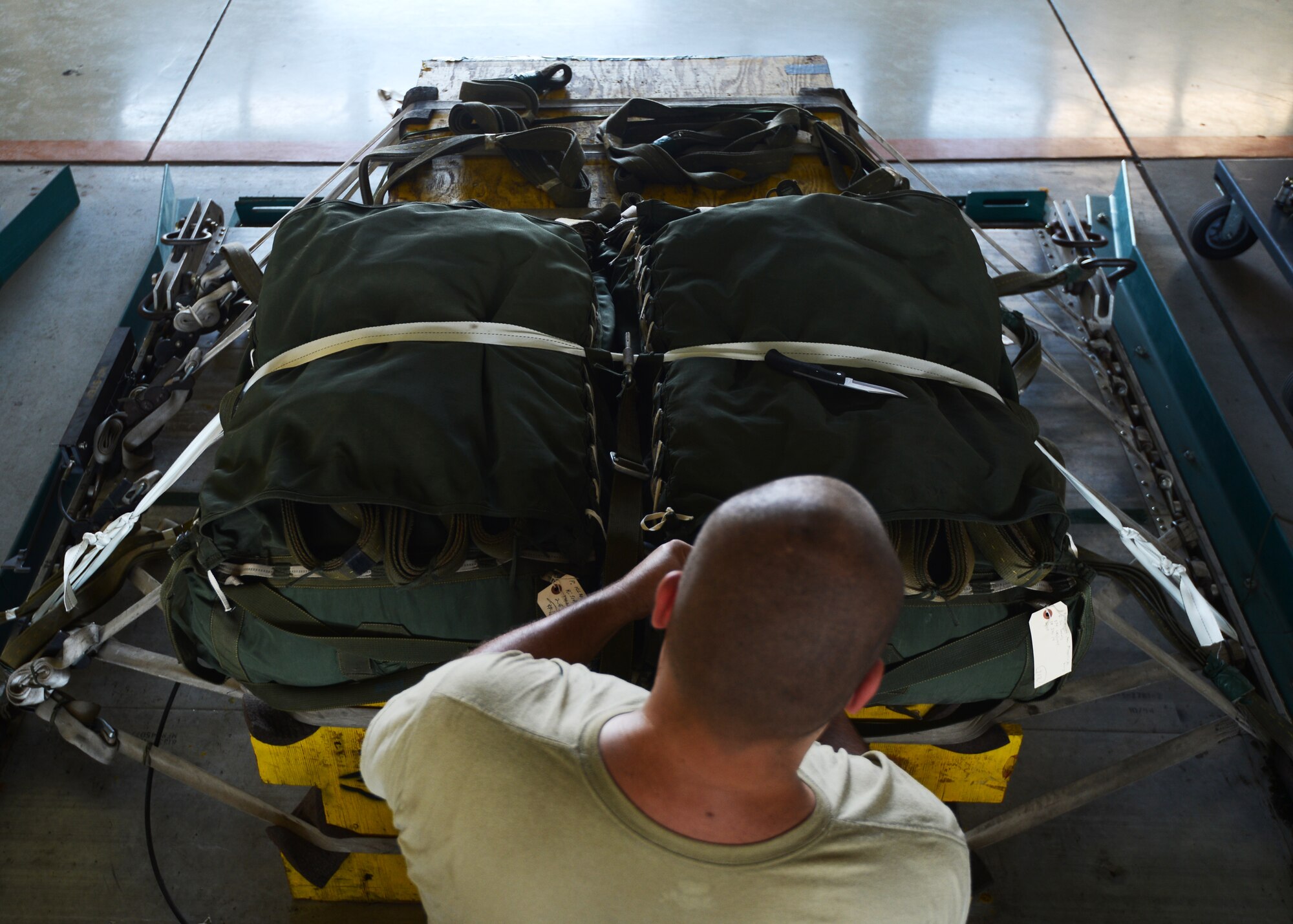 U.S. Air Force Senior Airman David Daniels, 730th Logistics Readiness Squadron Combat Mobility Flight, works to put together simulated cargo for a pallet drop, Yokota Air Base, Japan, Aug. 11, 2014. The pallets Daniels puts together are heavy platforms, weighing 5,000 pounds each, and Container Delivery Systems, weighing 800 to 1,000 pounds each, which simulates cargo being dropped during a real-world mission. (U.S. Air Force photo by Senior Airman Justyn M. Freeman/Released)