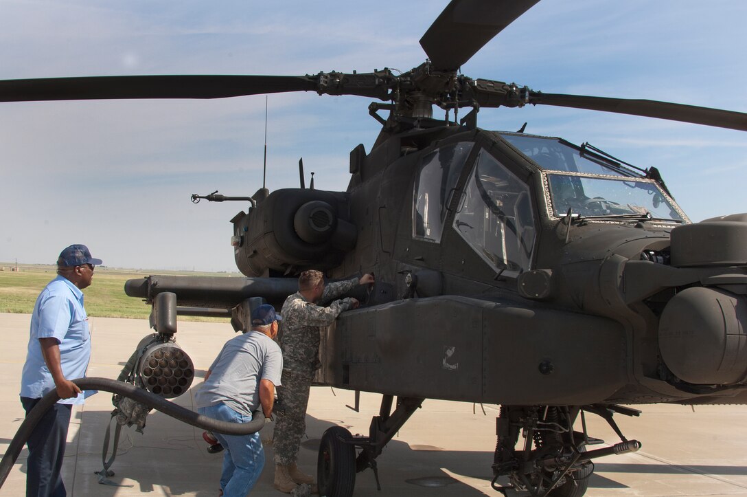 Three U.S. Army, AH 64 Delta Apache helicopters land at Sheppard Air Force Base, Texas, for refueling enroute to Fort Carson, Colo., on Aug. 14, 2014. U.S. Army Chief Warrant Officer 2 Anthony Bailey, opens the fuel port to refuel his helicopter with the assistance of James Wallace and Sammy Ellis base contractors from refuel management. (U.S. Air Force photo by Danny Webb/Released)
