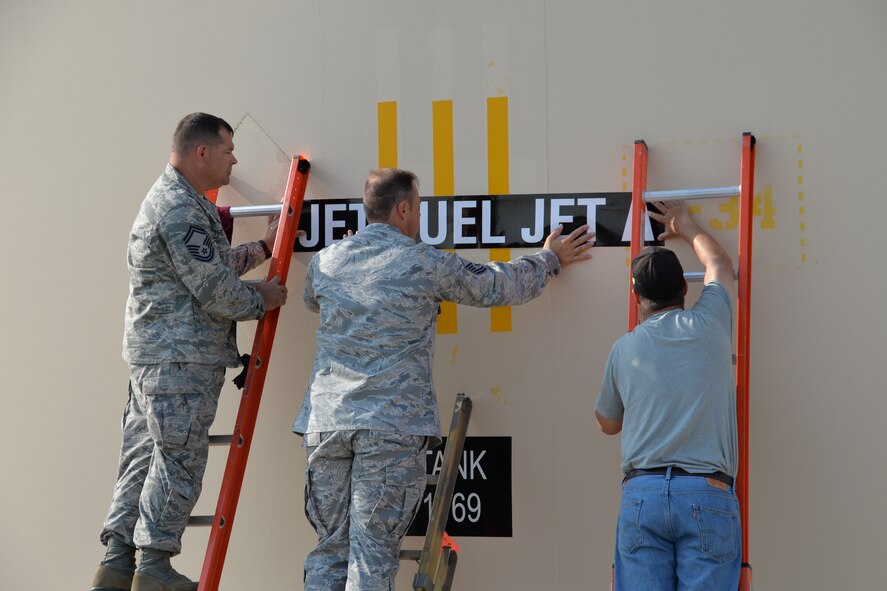 (Left to right) Senior Master Sgt. Charles Fetterolf, Master Sgt. Brad West and Larry Reddish, all from the Air Force Petroleum Agency, replace labels on the fuel storage tanks after Travis Air Force Base fully converted from using JP-8 to Jet A fuel August 6. The switch will save Travis and the Air Force millions of dollars in the coming years. (U.S. Air Force photo/Senior Airman Bryan Swink)