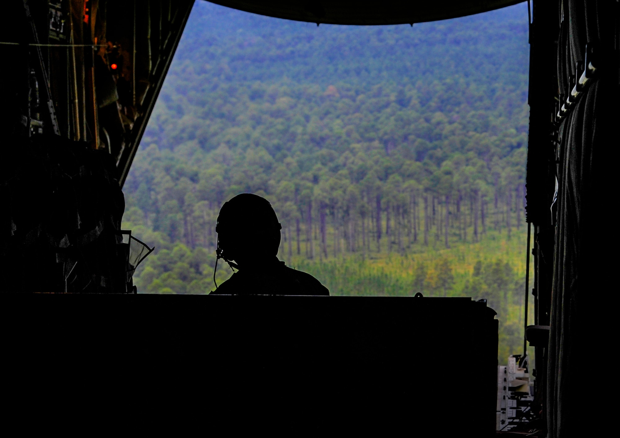 A 19th Airlift Wing loadmaster looks out the back of a C-130J July 31, 2014 over Ft. Polk, La. The Airman was preparing for an air drop as part of a large-scale joint readiness exercise. (U.S. Air Force photo by Airman 1st Class Harry Brexel)