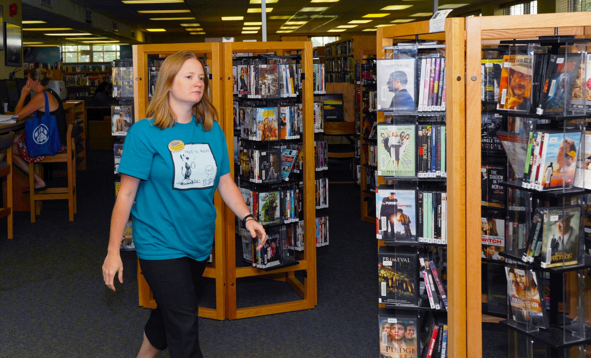 Becca Robins, Little Rock Air Force Base Library aide, returns to the front desk July 22, 2014, at Little Rock Air Force Base, Ark.  Technicians and aides in the library perform many duties to keep the library functioning for the base public. (U.S. Air Force photos by Airman 1st Class Mercedes Muro) 
