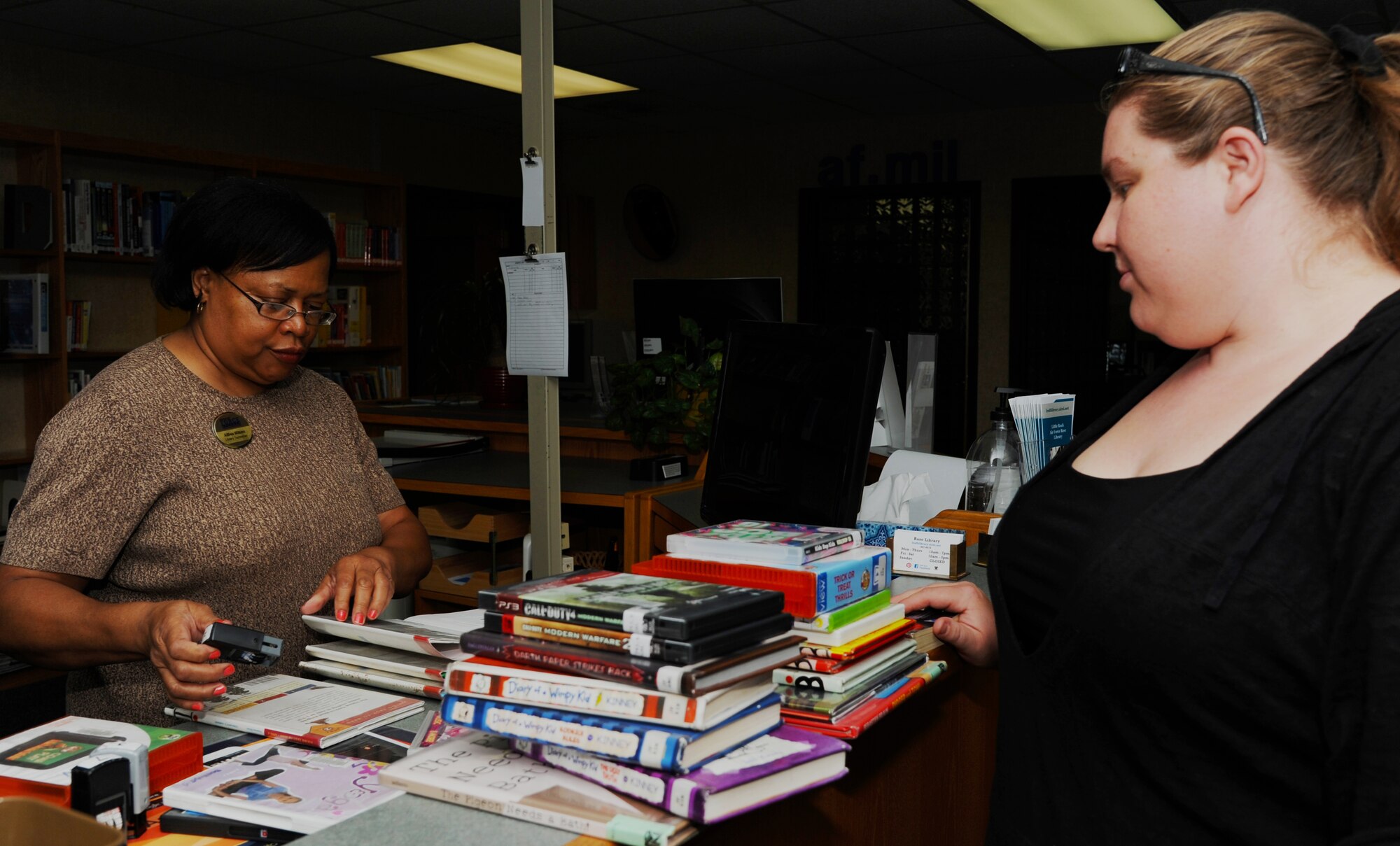 Althea Wilkins, Little Rock Air Force Base Library technician, checks out books to a customer July 22, 2014, at Little Rock Air Force Base, Ark.  People with access to the library can borrow large amounts of reading material, audio books and DVDs at one time. (U.S. Air Force photo by Airman 1st Class Mercedes Muro) 