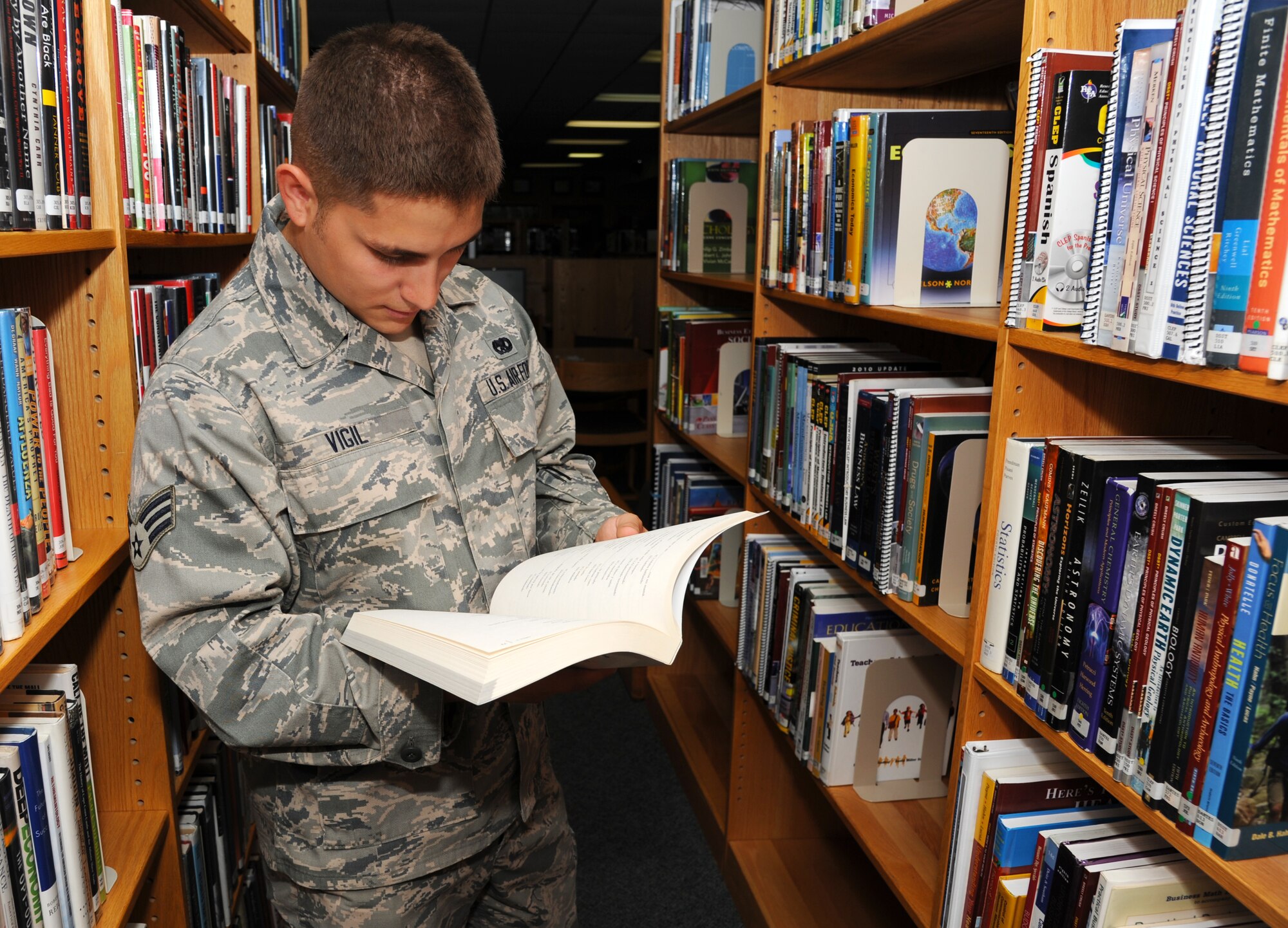Senior Airman Michael Vigil, a 19th Maintenance Squadron non-destructive inspection examiner, looks through a College Level Examination Program book July 22, 2014, at Little Rock Air Force Base, Ark. The library offers numerous CLEP and Defense Activity for Non-Traditional Education Support books that Airman can use to earn an exemption from a college course. (U.S. Air Force photo by Airman 1st Class Mercedes Muro) 
