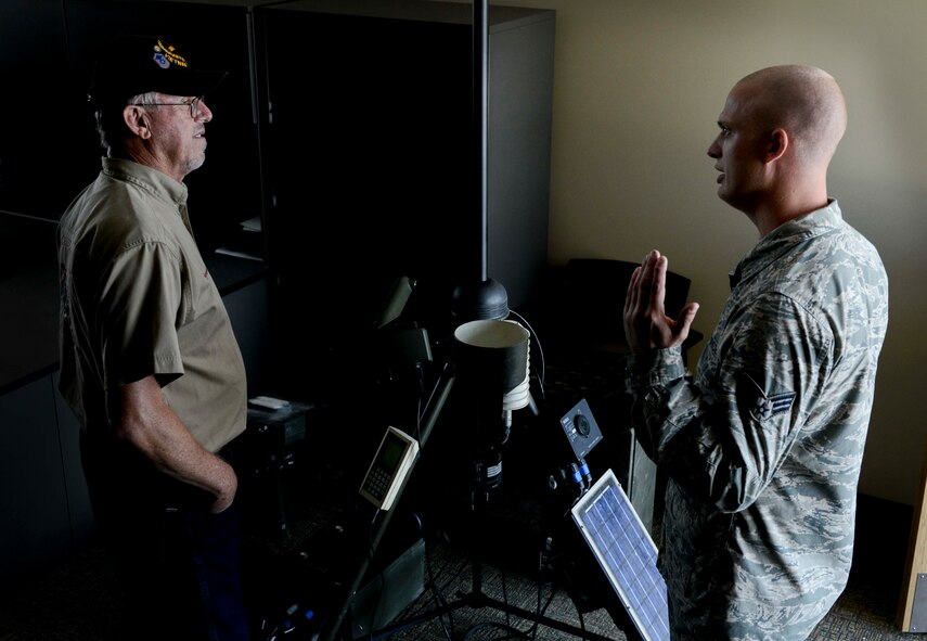 Retired Senior Master Sgt. Dennis Miller discusses a tactical meteorological observing system with Senior Airman Scott Hilde, 5th Operations Squadron weather forecaster, on Minot Air Force Base, N.D., Aug. 8, 2014. During his career Miller worked at Air Force Communications Command, Scott AFB, Illinois, as a program manager charged with finding new technology for weather equipment, training Airmen on its use, organizing logistics and field testing. (U.S. Air Force photo/Senior Airman Stephanie Morris.)