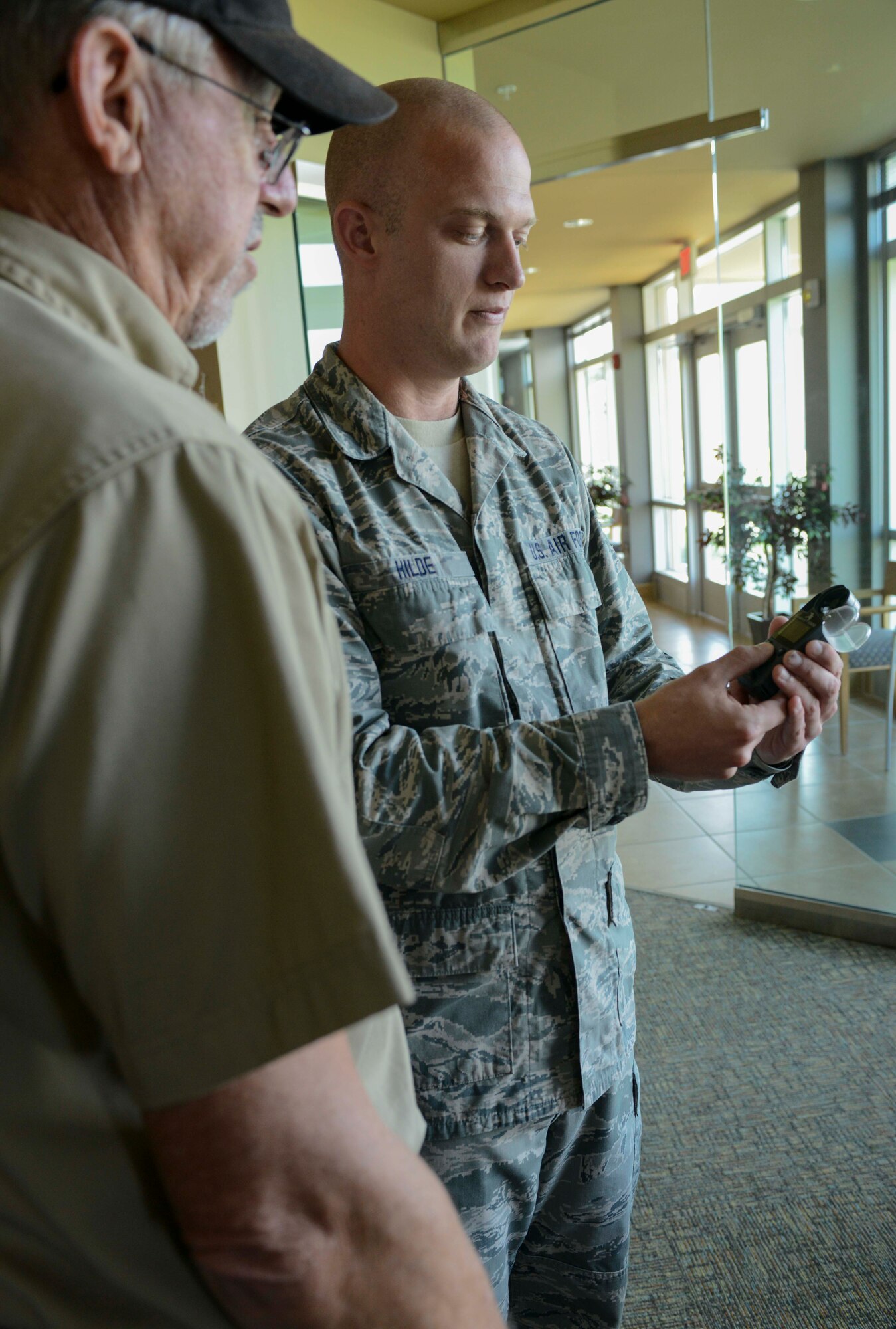 Retired Senior Master Sgt. Dennis Miller is shown an instrument used to assist with weather forecasting by Senior Airman Scott Hilde, 5th Operations Squadron weather forecaster, on Minot Air Force Base, N.D., Aug. 8, 2014. The two discussed the advances that have been made in forecast technology, as well as the availability of new weather analysis programs. (U.S. Air Force photo/Senior Airman Stephanie Morris.)
