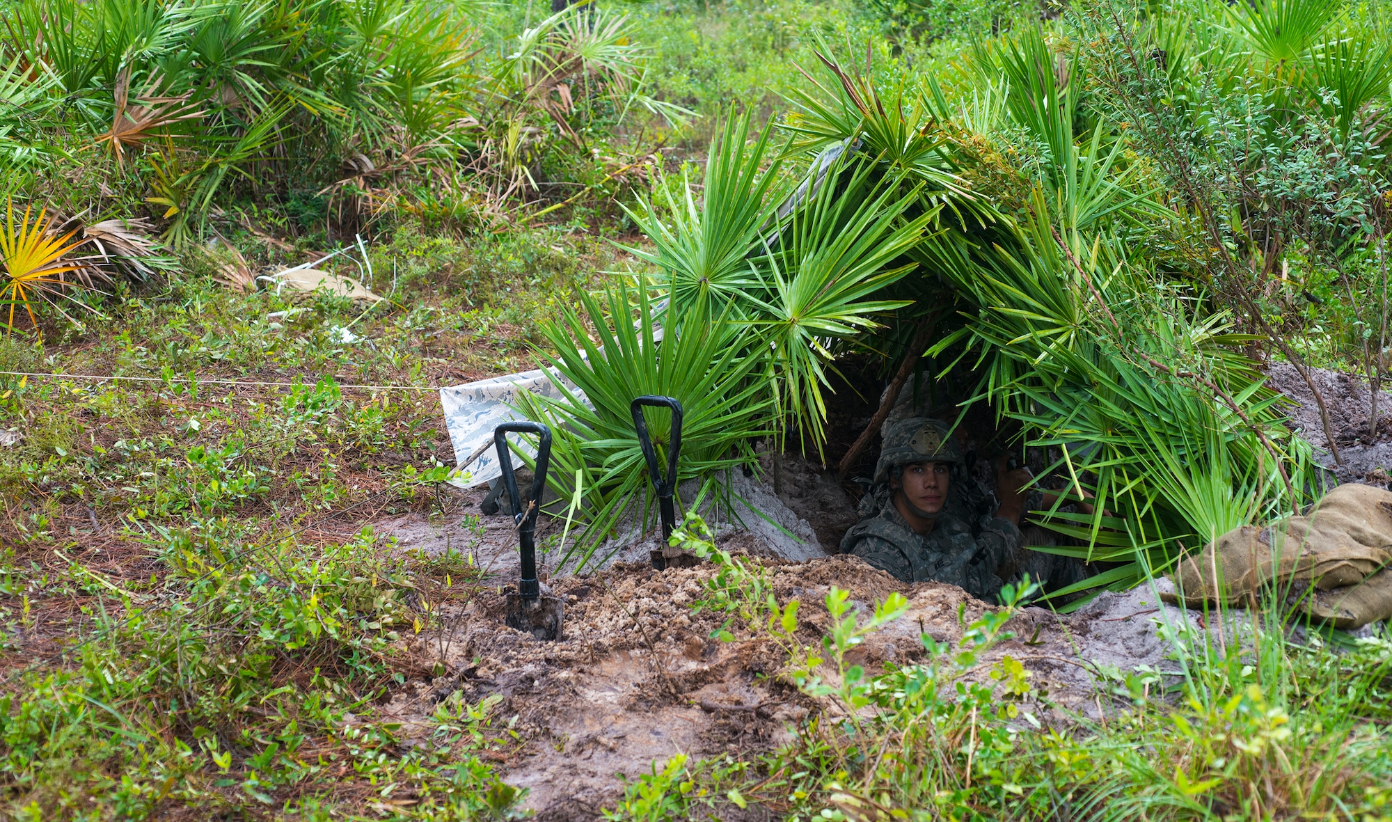 U.S. Air Force Senior Airman Joshua McKee, 823d Base Defense Squadron fire team member, searches for friendly or hostile movement during exercise Safeside Guardian at Camp Blanding, Fla., Aug. 12, 2014. Harris created his defensive fighting position by digging a hole and covering it with a natural concealment. (U.S. Air Force photo by Airman 1st Class Ceaira Tinsley/Released)