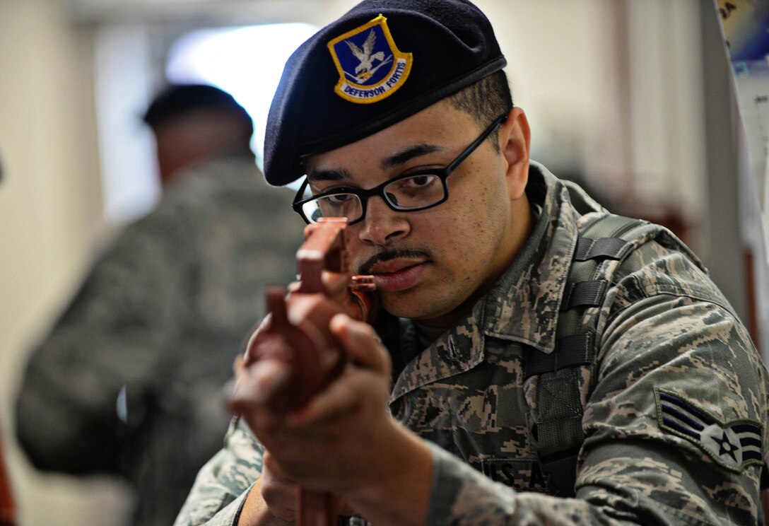 Senior Airman Max Hoagland, 28th Security Forces Squadron patrolman, guards a hallway as his team prepares to move during an active shooter exercise at Ellsworth Air Force Base, S.D., Aug. 12, 2014. The Airmen entered the 28th Communications Squadron headquarters to engage suspects, eliminate the threat to the base, assess casualties and report information to emergency responders. (U.S. Air Force photo by Senior Airman Zachary Hada/Released)
