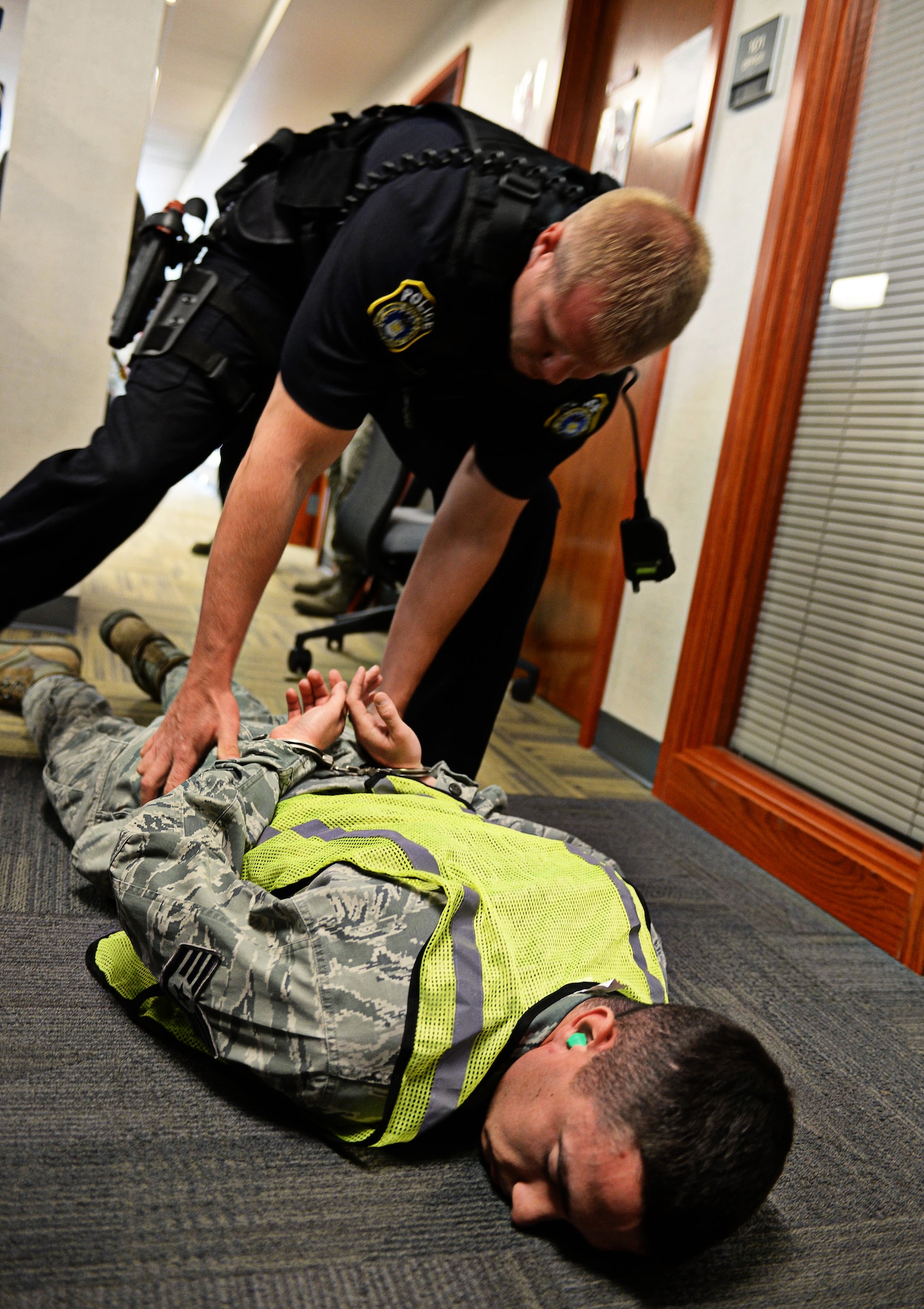 Clayton Denney, 28th Security Forces Squadron security officer, apprehends Staff Sgt. Lance Bradshaw, 28th Communications Squadron voice networks NCO in charge, as part of an active shooter exercise at Ellsworth Air Force Base, S.D., Aug. 12, 2014. The purpose of the exercise was to test reaction and response time of the 28th Bomb Wing to an active shooter scenario. (U.S. Air Force photo by Senior Airman Zachary Hada/Released)