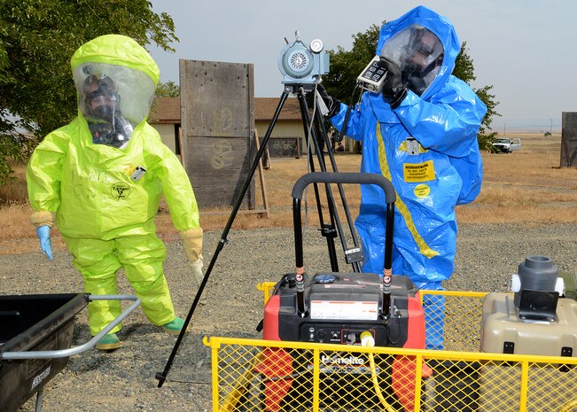 Airmen from 9th Aerospace Medicine Squadron utilize air sampling equipment during an emergency services exercise at Beale Air Force Base, Calif., Aug. 8, 2014. The Airmen are wearing protective suits which provide protection from all forms of chemicals: solids, liquids, and gasses/vapors. (U.S. Air Force photo by John Schwab/Released)