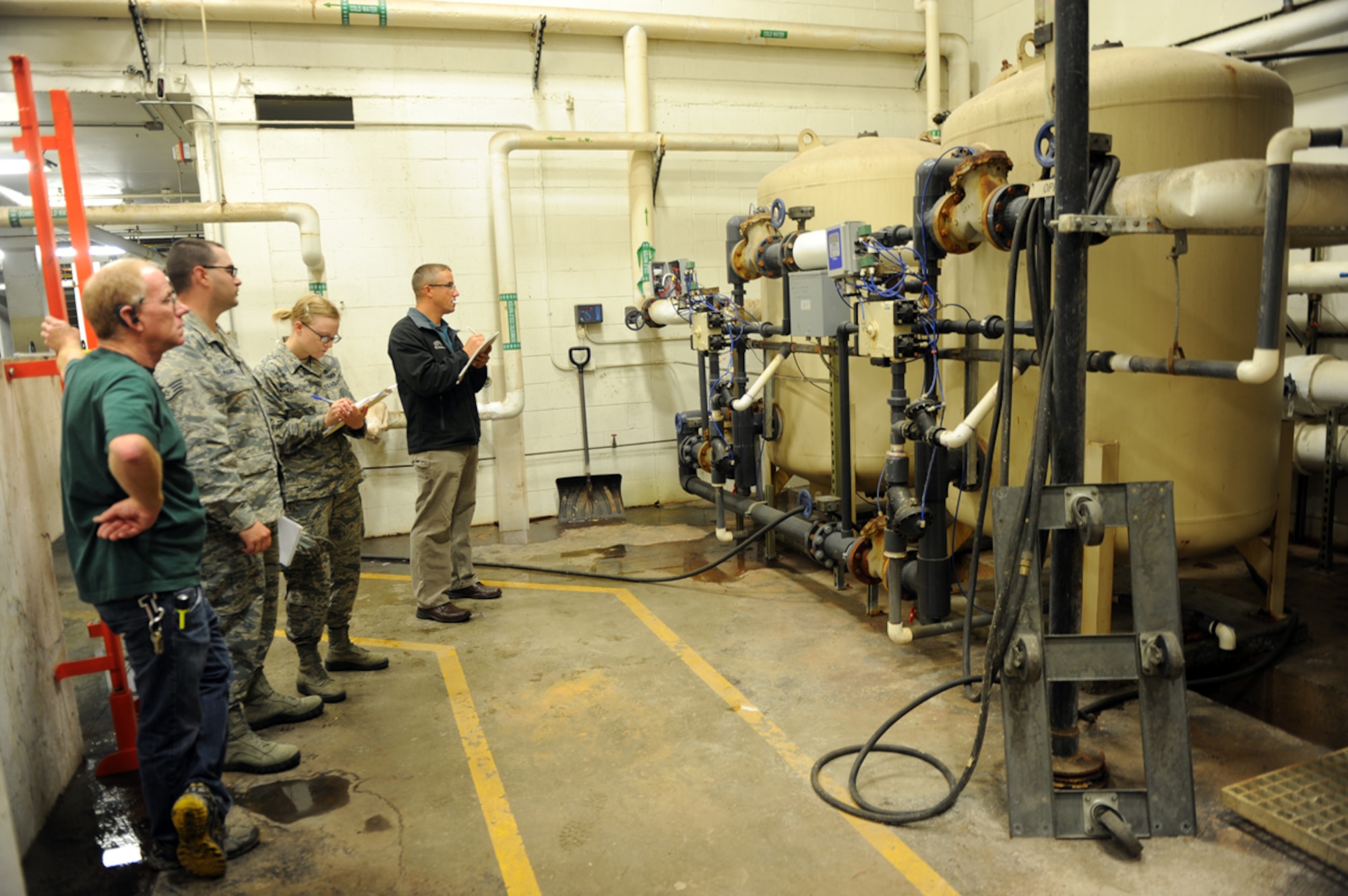 Staff Sgt. Chris Palmer, 673d Contracting Squadron contract officer, and Airman 1st Class Katrina Kappele, 673d CONS contract administrator, review a non-functioning water filtration system at the Quartermaster Laundry, August 12, 2014, on Joint Base Elmendorf-Richardson. The contracting squadron shows potential clients what they will be contracted to work on so they can make a bid to win the contract to fix the system. (U.S Air Force Photo/ Senior Airman Omari Bernard)