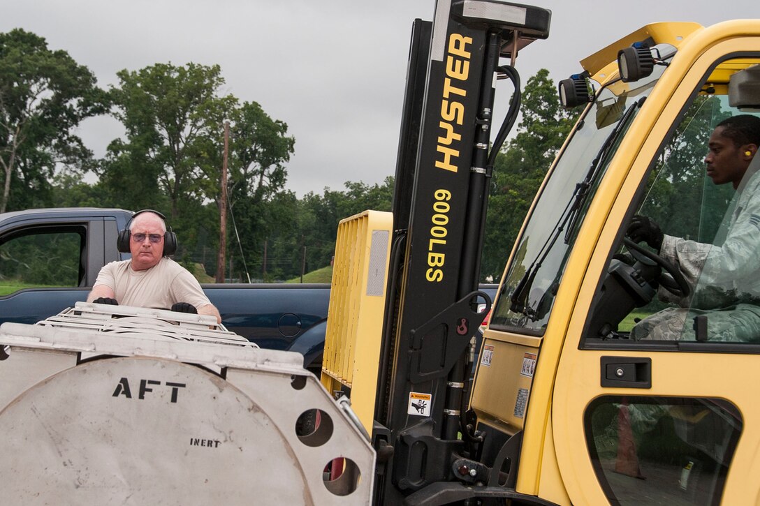 U.S. Air Force Tech. Sgt. John Carter, munitions storage shop chief, 307th Maintenance Squadron, directs forklift operator Senior Airman Toris Flowers, during the receiving of a Training Guided Missile, July 24, 2014, at Barksdale Air Force Base, La. The Airmen are storage crew members assigned to the 307 MXS and are responsible for making sure all the other munitions shops have the bomb making components they need to accomplish their daily work load. (U.S. Air Force photo by Master Sgt. Jeff Walston/Released)