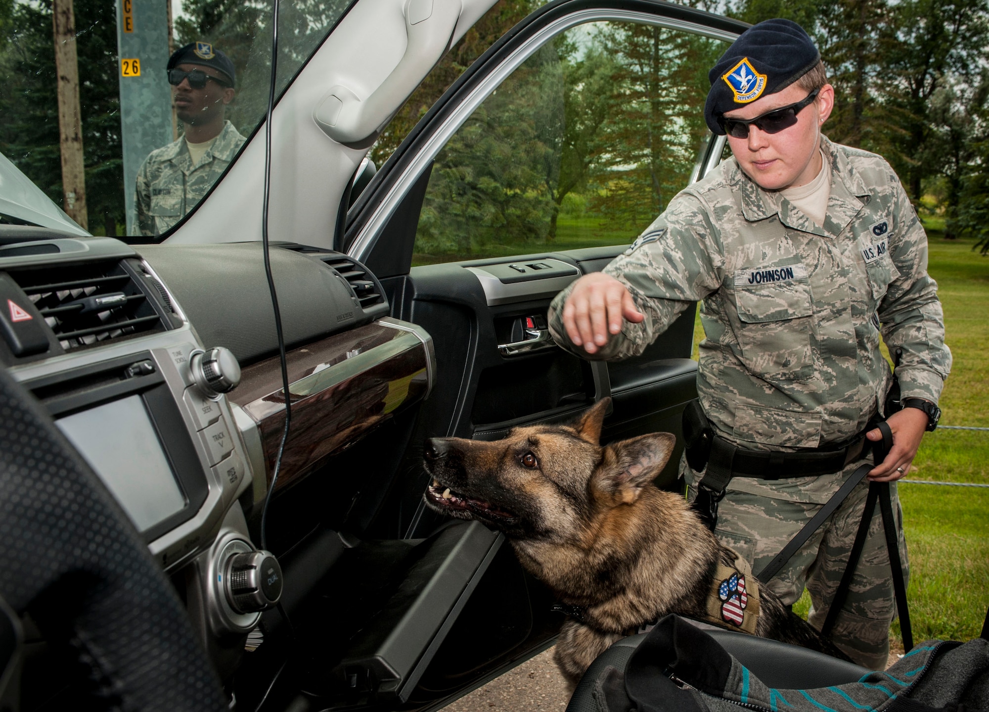 Senior Airman Heather Johnson, 5th Security Forces Squadron military working dog handler, gives her MWD Cyndy the command “seek” during a vehicle inspection on Minot Air Force Base, N.D., July 29, 2014. In addition to their duties on the base, Johnson and Cyndy also provide security for events off base. The two perform demonstrations for the local community, security checks for downtown events and at venues for Air Force events such as the Air Force Ball. (U.S. Air Force photo/Senior Airman Stephanie Morris)