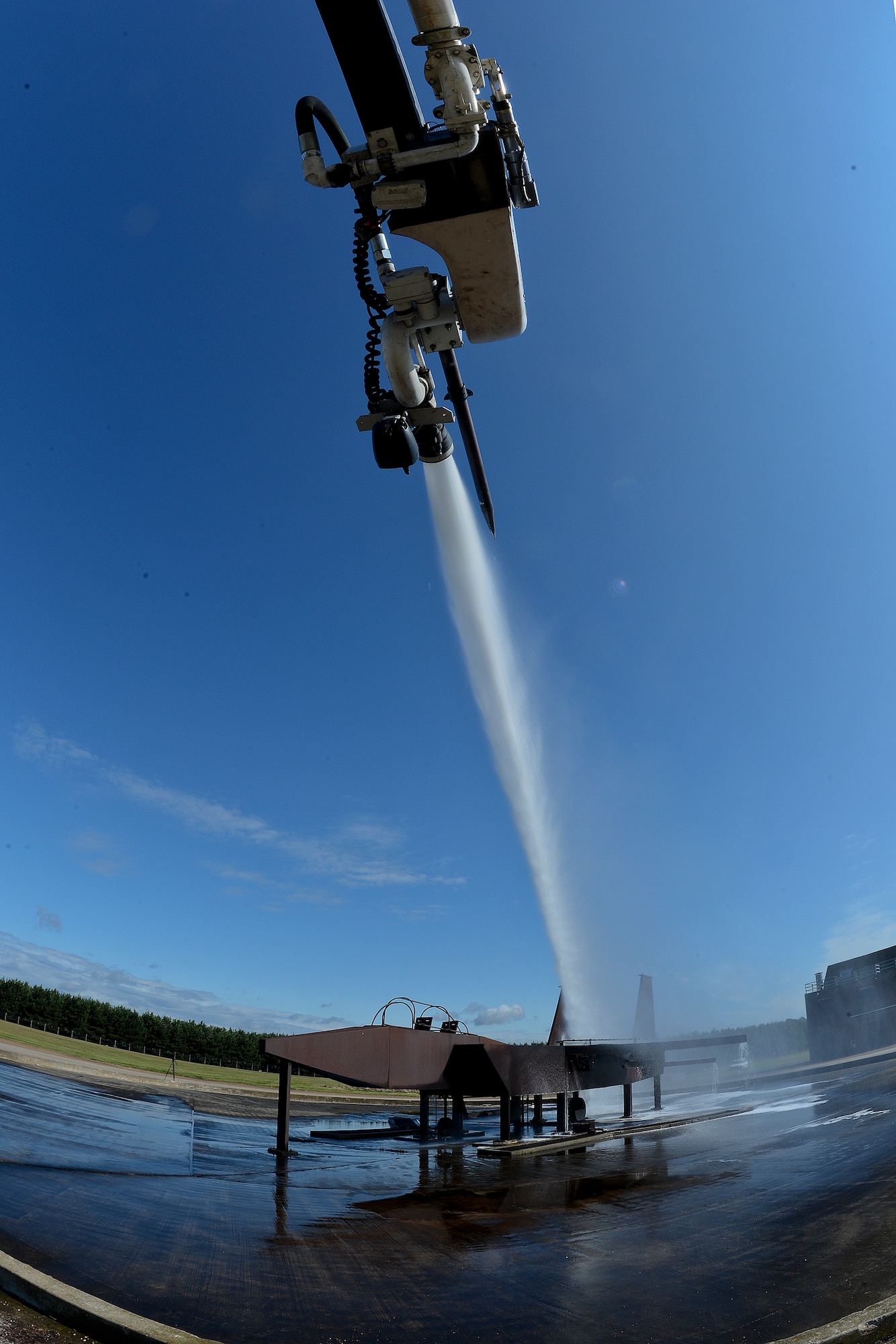 A 48th Civil Engineer Squadron Fire Department firefighter sprays water during live fire training at the burn pit on Royal Air Force Lakenheath, England, Aug. 13, 2014. Live fire training ensures firefighters are able to save lives and protect government assets by performing required core tasks in the event of an aircraft fire. (U.S. Air Force photo by Airman 1st Class Trevor T. McBride/Released)