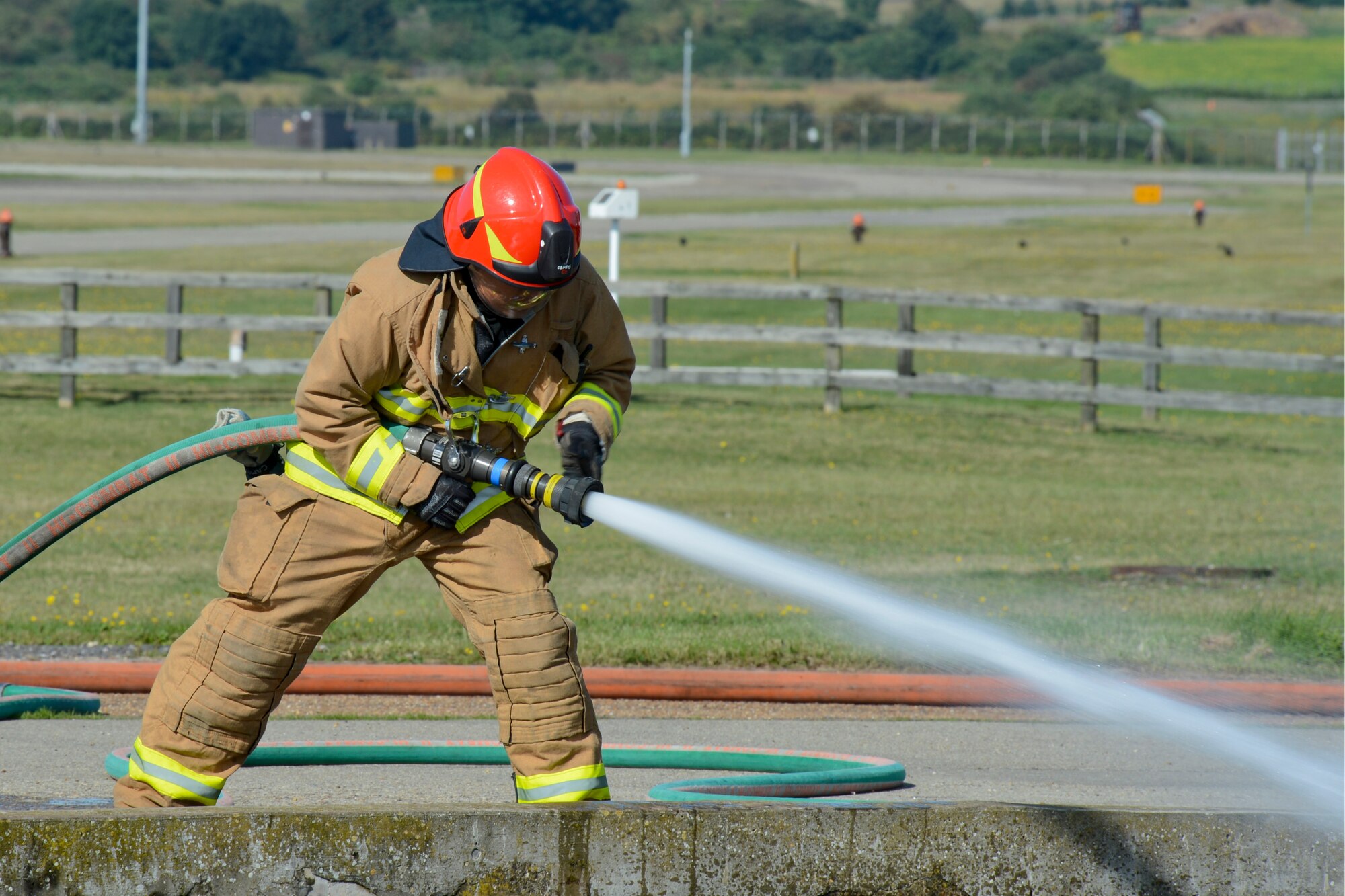 A 48th Civil Engineer Squadron Fire Department firefighter sprays water during live fire training at the burn pit on Royal Air Force Lakenheath, England, Aug. 13, 2014. Live fire training ensures firefighters are able to save lives and protect government assets by performing required core tasks in the event of an aircraft fire. (U.S. Air Force photo by Airman 1st Class Trevor T. McBride/Released)