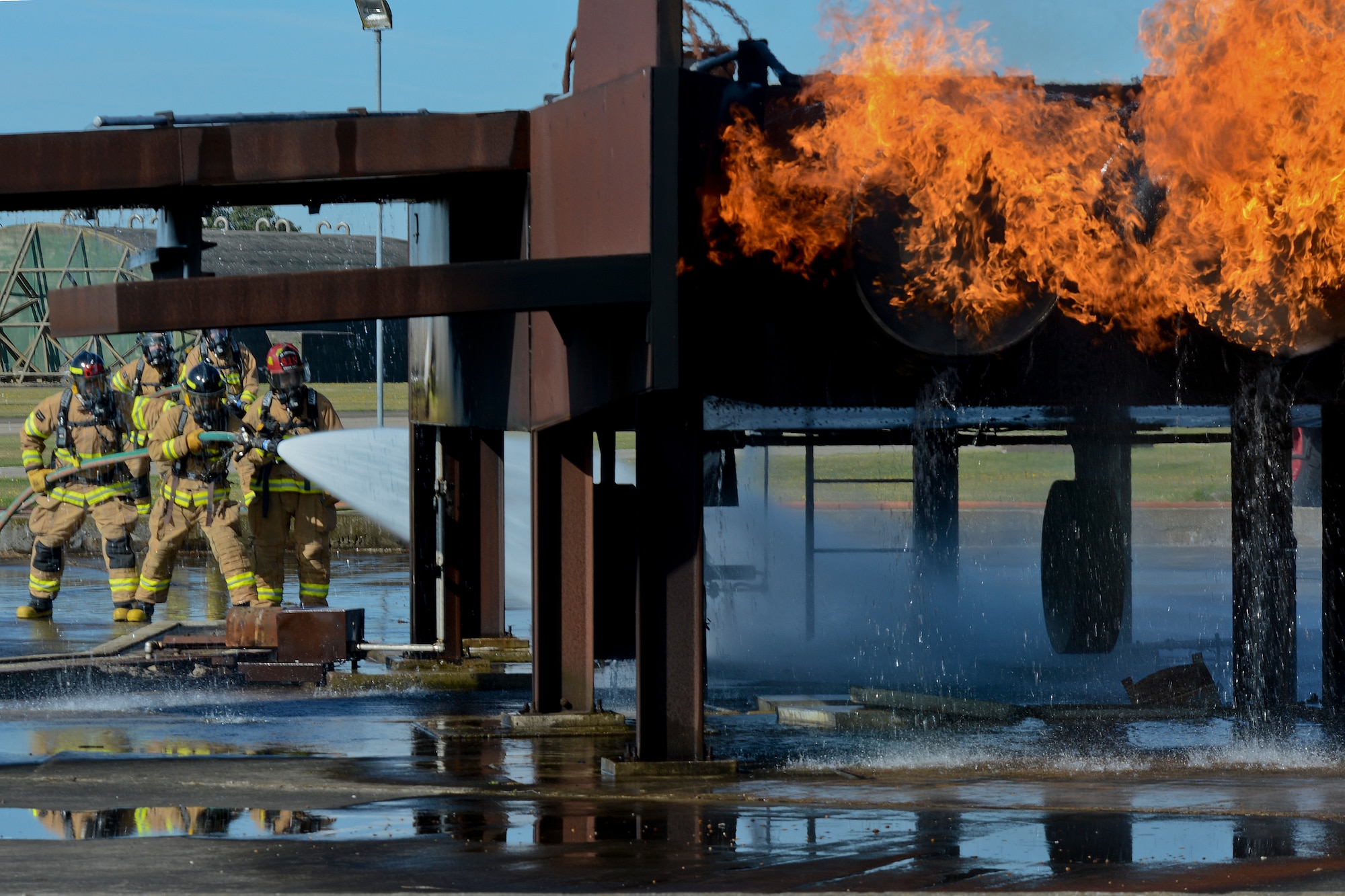 Firefighters of the 48th Civil Engineer Squadron Fire Department spray a mock F-15 with water during live fire training at the burn pit on Royal Air Force Lakenheath, England, Aug. 13, 2014. Live fire training ensures firefighters are able to save lives and protect government assets by performing required core tasks in the event of an aircraft fire. (U.S. Air Force photo by Airman 1st Class Trevor T. McBride/Released)