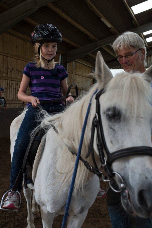 Sophie Dickson, daughter of Shanna Dickson, rides a horse led by Hans Freiwald, Spangdahlem horse rancher, during the Exceptional Family Member Program camp at Spangdahlem, Germany, Aug. 12, 2014. EFMP improves quality of life for special needs families. (U.S. Air Force photo by Staff Sgt. Christopher Ruano/Released)