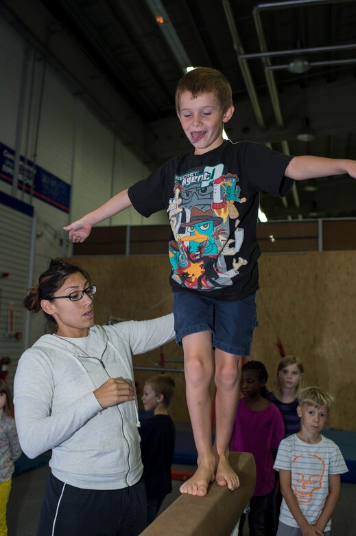 Cat Schnoes, gymnastics coach, wife of U.S. Air Force Tech. Sgt. Karl Schnoes, 52nd Civil Engineer Squadron firefighter, instructs Ethan Fisher, son of Shelli Tiff, how to walk on a balance beam during the Exceptional Family Member Program camp at Bitburg Annex, Germany, Aug. 12, 2014. The EFMP works with military families with special needs children to address and accommodate their specific needs at their installation. (U.S. Air Force photo by Staff Sgt. Christopher Ruano/Released)