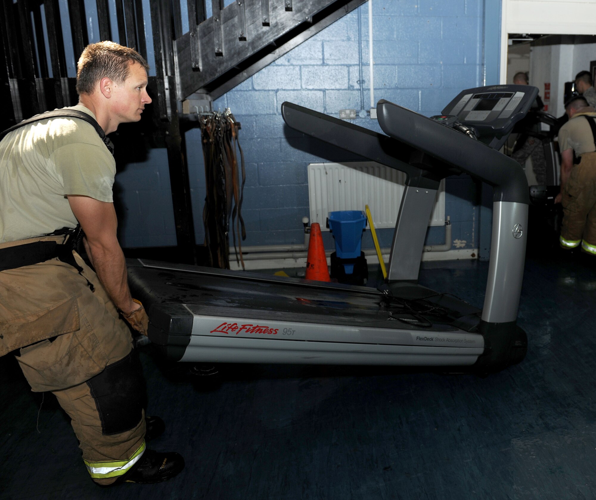 U.S. Air Force Staff Sgt. Christopher Bryant, 100th Civil Engineer Squadron Fire Department fire protection crew chief from Stockton, Calif., removes a treadmill from the Northside Fitness Center's cardio room after a pipe burst Aug. 12, 2014, on RAF Mildenhall, England. The burst pipe caused minor flooding and damage in the Northside Fitness Center, which will be closed until further notice. The Hardstand Fitness Center has adjusted its operating hours to accommodate for this closure.  (U.S. Air Force photo/Senior Airman Kate Maurer/Released) 
