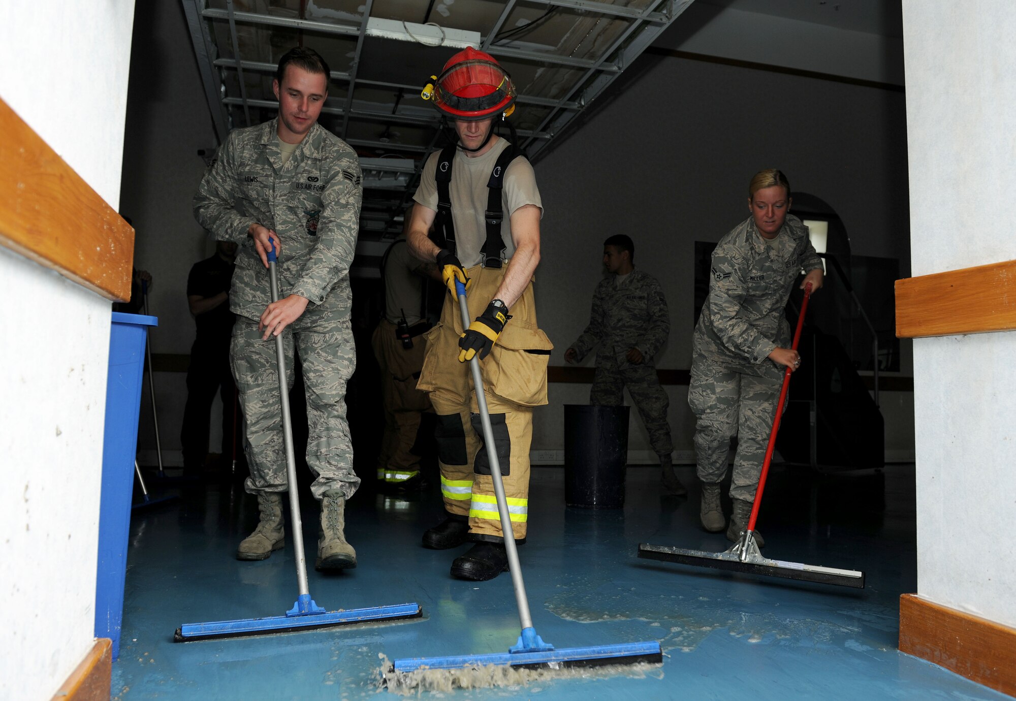 From left, U.S. Air Force Senior Airman Josh Lewis, 100th Civil Engineer Squadron Fire Department driver and operator from San Antonio, Texas; U.S. Air Force Staff Sgt. David Jeghers, 100th CES Fire Department crew chief from Holmehale, Norfolk; and U.S. Air Force Airman 1st Class Lauren Miller, 100th Force Support Squadron Military Personnel Section career development specialist from Erie, Pa.; squeegee water out of the Northside Fitness Center 's cardio room after a pipe burst Aug. 12, 2014, on RAF Mildenhall, England. The burst pipe caused minor flooding and damage in the Northside Fitness Center, which will be closed until further notice. The Hardstand Fitness Center has adjusted its operating hours to accommodate for this closure. (U.S. Air Force photo/Senior Airman Kate Maurer/Released)

