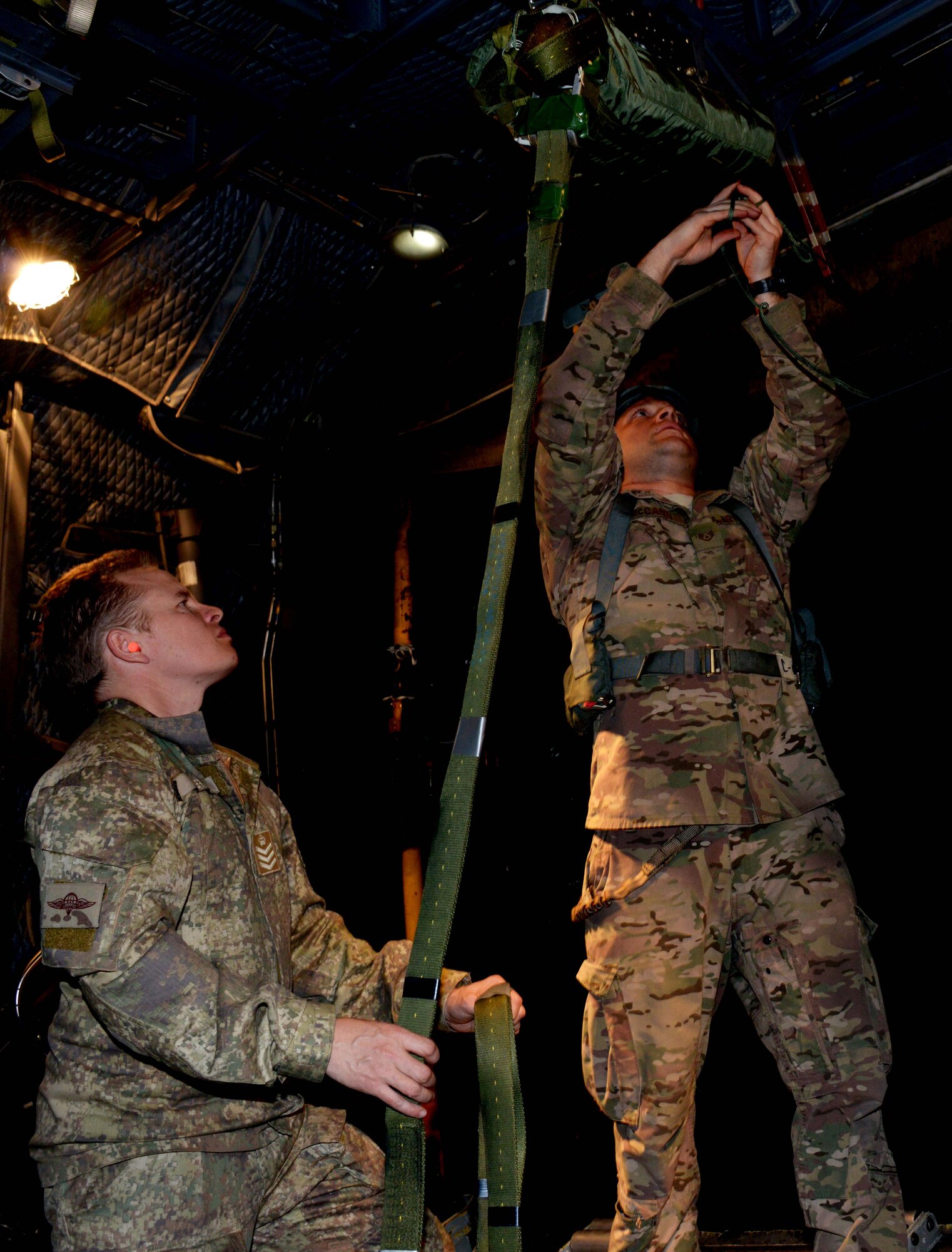 Staff Sgt. Brian McCann, a loadmaster at the 1st Special Operations Squadron, works with a member from the New Zealand Defense Force to rig the extraction parachute for a heavy equipment drop July 28, 2014.  Members from the 353rd Special Operations Group participated in Exercise Balance Net July 17 through July 31 in Whenuapai, New Zealand. During the exercise, members from both the New Zealand Defense Force and U.S. Air Forces worked together to conduct personnel and equipment air drops while exchanging new techniques. This was the first time in almost three decades the group has deployed to New Zealand.  (U.S. Air Force photo by Tech. Sgt. Kristine Dreyer)