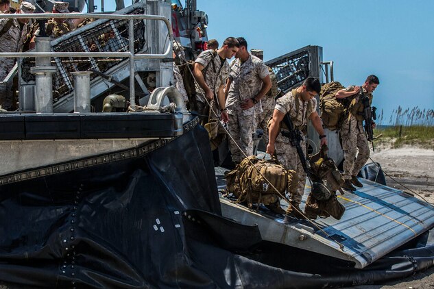 Marines and Sailors disembark a Landing Craft Air Cushion, or LCAC, from the USS Iwo Jima’s Assault Craft Unit 4, during a tactical offload of 24th Marine Expeditionary Unit personnel and equipment at Onslow Beach, N.C., August 12, 2014. The offload was part of Amphibious Squadron/Marine Expeditionary Unit Integration, the second major exercise for the 24th MEU. The USS Iwo Jima is part of the Iwo Jima Amphibious Ready Group. (U.S. Marine Corps photo by Cpl. Mary M. Carmona)