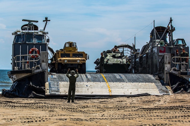 A Marine with the Landing Force Shore Party, or LFSP, navigates the Combat Anti-Armor Team, or CAAT, with the 24th Marine Expeditionary Unit’s Ground Combat Element, Battalion Landing Team 3rd Battalion, 6th Marine Regiment, off a Landing Craft Air Cushion, or LCAC, from the USS Iwo Jima’s Assault Craft Unit 4, during a tactical offload of 24th MEU personnel and equipment at Onslow Beach, N.C., August 12, 2014. The offload was part of Amphibious Squadron/Marine Expeditionary Unit Integration, the second major exercise for the 24th MEU. The USS Iwo Jima is part of the Iwo Jima Amphibious Ready Group. (U.S. Marine Corps photo by Cpl. Mary M. Carmona)