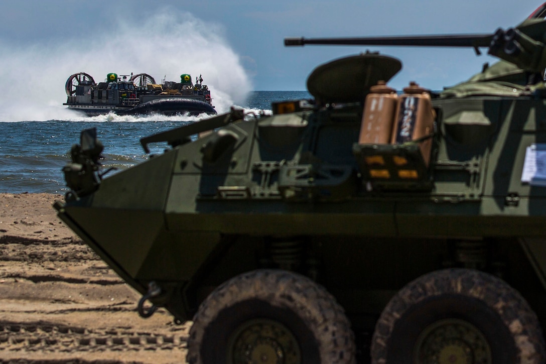 A Light Armored Vehicle with the 24th Marine Expeditionary Unit’s Ground Combat Element, Battalion Landing Team 3rd Battalion, 6th Marine Regiment, provides security as a landing craft air cushion from the USS Iwo Jima’s Assault Craft Unit 4 during a tactical offload of 24th MEU personnel and equipment near Onslow Beach, North Carolina, Aug. 12, 2014. The offload was part of Amphibious Squadron/Marine Expeditionary Unit Integration, the second major exercise for the 24th MEU. The AAV’s were launched from the USS Arlington and USS Iwo Jima, both a part of the Iwo Jima Amphibious Ready Group.