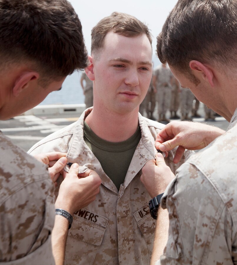 U.S. 5TH FLEET AREA OF RESPONSIBILITY (Aug. 1, 2014) U.S. Marines with Battalion Landing Team (BLT) 1st Battalion, 6th Marine Regiment, 22nd Marine Expeditionary Unit (MEU), promote Cpl. Connor Bowers, BLT 1/6 intelligence analyst and native of Temecula, Calif., to his current rank aboard the amphibious transport dock ship USS Mesa Verde (LPD 19). The 22nd MEU is deployed with the Bataan Amphibious Ready Group as a theater reserve and crisis response force throughout U.S. Central Command and the U.S. 5th Fleet area of responsibility. (U.S. Marine Corps photo by Staff Sgt. Lukas Atwell / Released)