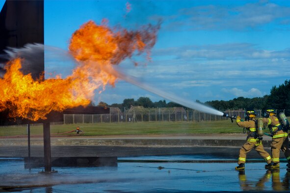 Firefighters of the 48th Civil Engineer Squadron Fire Department spray a mock F-15 Eagle engine with water during live-fire training Aug. 13, 2014, at the burn pit on Royal Air Force Lakenheath, England. All firefighters are required to conduct live-fire training twice a year to avoid skill fade and keep their qualifications current. (U.S. Air Force photo/Airman 1st Class Trevor T. McBride)