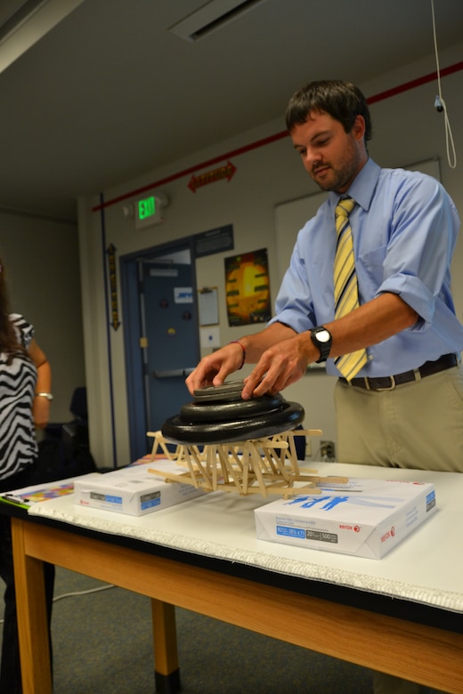 Engineer Jimmy Swiggett places weights on a popsicle bridge to see how much weight it can hold. The activity was part of a presentation by engineers from the District about engineering.