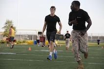 Beau A. Bequeaith, a senior Blue Valley High School Tigers tight end, grimaces as he sprints with two 30-pound ammunition cans as part of the Marine Corps Combat Fitness Test as Sgt. Laronald McKinney, a Marine Corps Recruiting Station Kansas City, Recruiting Sub-Station Olathe recruiter, sprints ahead to motivate Bequeaith to the end. The CFT is substantially different from a normal regiment of football and was seen as a way to shake up the usual routine pf practice before the season starts.