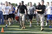 Sergeants Laronald McKinney, left, and Michael Socin, right, Marine Corps Recruiting Station Kansas City, Recruiting Sub-Station Olathe recruiters, demonstrates aspects of the Marine Corps' Combat Fitness Test as the Blue Valley High School Tigers football team follows alongside at the Lamar District Athletic complex Aug. 14, 2014. 