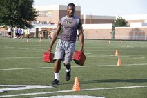Gannon C. Cornley, a senior Blue Valley High School Tigers cornerback, running back, and wide receiver, performs cone drills while carrying two 30-pound ammunition cans during the Marine Corps' Combat Fitness Test at the Lamar District Athletic Complex Aug. 14, 2014. Marines from Recruiting Station Kansas City and Recruiting Sub-Station Olathe psuhed the players to dig deep and finish strong. The CFT consists of an 880-meter sprint, ammo-can lifts in two minutes, and a maneuver-under-fire portion.