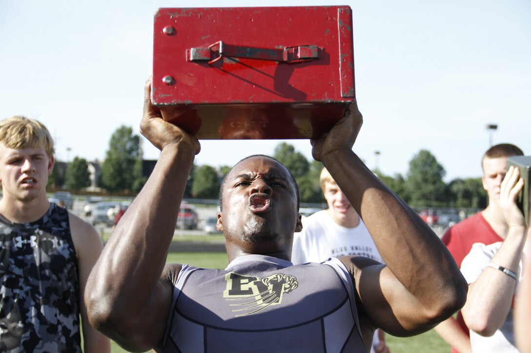 Gannon C. Cornley, a senior Blue Valley High School Tigers cornerback, running back, and wide receiver, exhales sharply as he presses a 30-pound ammunition can over his head during the Marine Corps' Combat Fitness Test as part of the Tigers offseason training at the Lamar District Athletic Complex Aug. 14, 2014. Marines from Marine Corps Recruiting Sub-Station Olathe were on hand to administer and supervise the CFT. Cornley performed more than 140 ammo-can lifts in the alloted two minutes. 