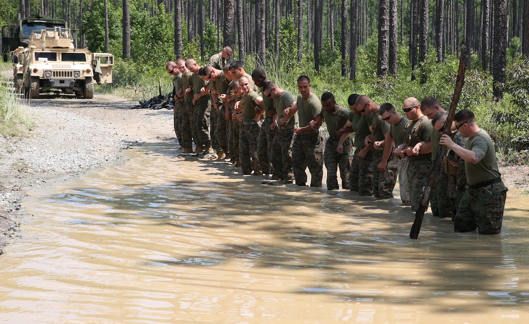 Marines with Motor Transportation Services Company, Combat Logistics Battalion 25, Combat Logistics Regiment 45, practice searching a water-fording navigation course at Camp Lejeune, North Carolina Aug. 13, 2014, during exercise Heavy Metal 14.  The Marines used a human chain in case the lead Marine became stuck, the others could pull him out. The lead Marine used a stick as an improvised measuring tool, to judge whether the fording area was safe for the next step.